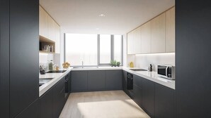 A modern kitchen with dark cabinetry, white countertops, and a central island. - Dominick Place (Dublin)