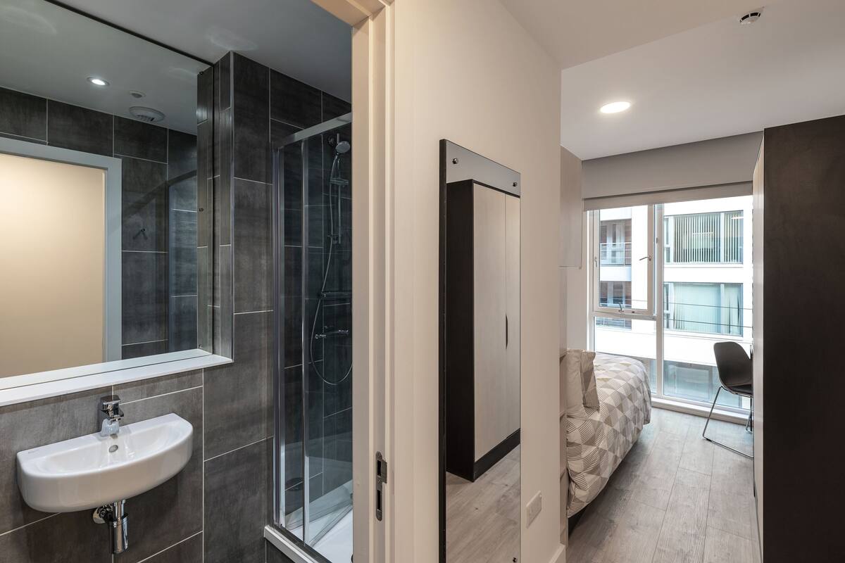 A modern bathroom with a glass shower, a sink, and a large mirror.