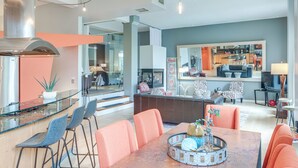 A modern kitchen with a large island, bar seating, and a dining area with orange chairs. - Dtwn Cleveland Loft-Style Condo: Walk to Stadiums! (Cleveland)