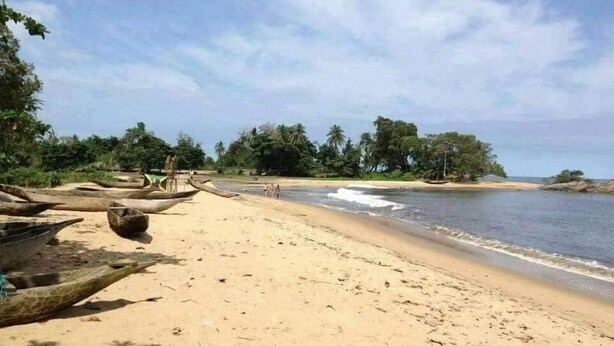 A sandy beach with several wooden boats and a calm sea. - Eden Lodge Kribi (Kribi)