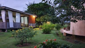 A wooden house with a porch, surrounded by a well-maintained garden with various plants and flowers. - Eden Lodge Kribi (Kribi)