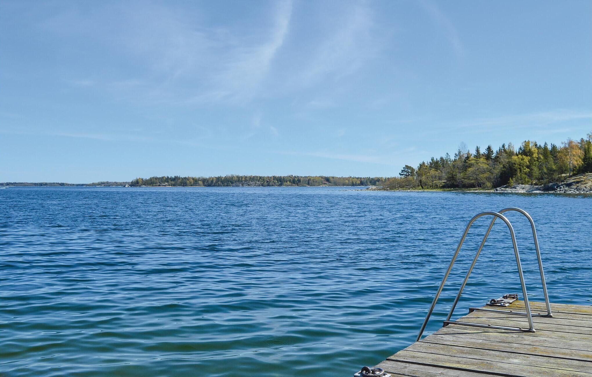 A wooden dock extending into a calm body of water with a clear sky above.