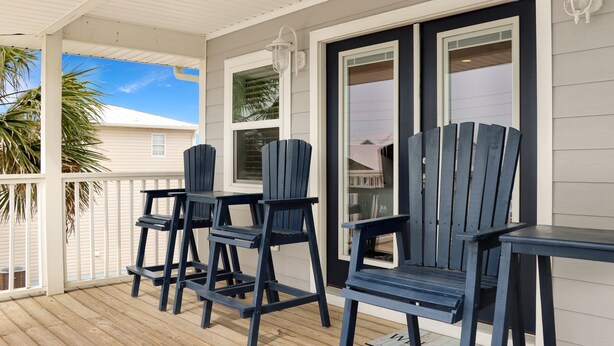 A covered porch with wooden flooring, white railings, and dark blue Adirondack chairs. - Steps To The Beach, Near Killer Seafood ~ Oleander Place (Mexico Beach)