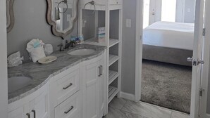 A bathroom with a marble sink, two mirrors, and a shower area. - Steps To The Beach, Near Killer Seafood ~ Oleander Place (Mexico Beach)