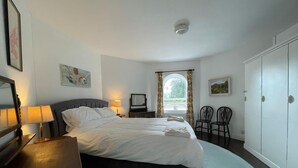 A bedroom with a bed, bedside lamps, a mirror, a dresser, a chair, and a wardrobe.