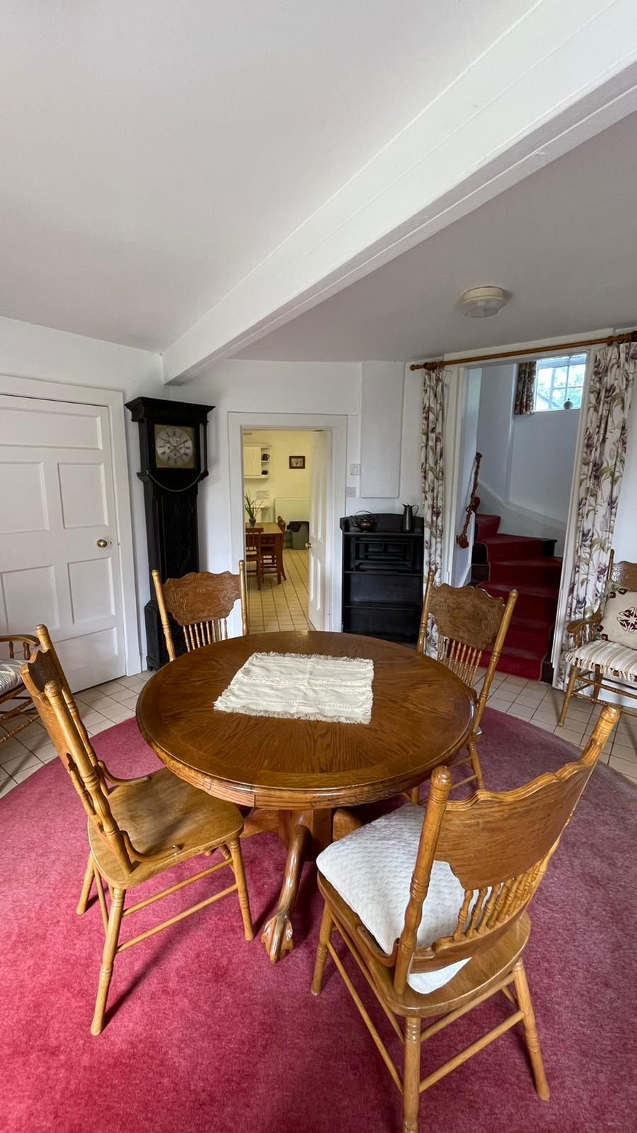 Un coin repas comprenant une table ronde en bois et six chaises, une moquette rouge et une cheminée noire.
