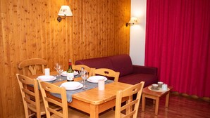 Un comedor con paredes de madera, una mesa de madera dispuesta para cuatro personas y una cortina roja al fondo.