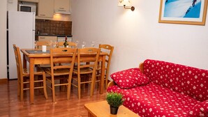 A compact living space with a dining area, a red patterned sofa, and a small table with a plant. - 3-Room Apartment, 6 People, Pets Allowed, Balcony (Le Dévoluy)