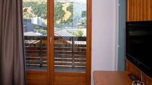 A room with a wooden door leading to a balcony with a view of a mountainous landscape and a cityscape. - 3-Room Apartment, 6 People, Pets Allowed, Balcony (Le Dévoluy)
