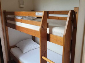 Uma cama beliche com estrutura de madeira e roupa de cama branca.
