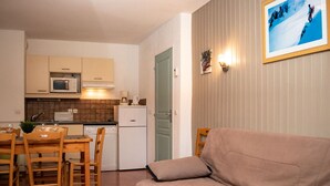 A compact living space with a kitchenette, a dining area with wooden furniture, and a sofa. - 3-room apartment for 6 people, mountain view, pets allowed (Le Dévoluy)