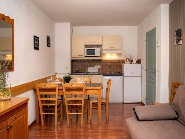 A compact kitchen with a dining area, wooden furniture, and a kitchenette. - 3-room apartment for 6 people, mountain view, pets allowed (Le Dévoluy)