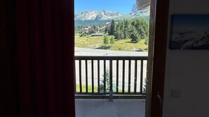 Un balcon offrant une vue sur un paysage montagneux, avec notamment un sommet imposant et un bâtiment doté d’un toit en forme de flèche.