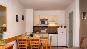 A compact kitchen with a dining area, wooden furniture, and a kitchenette.