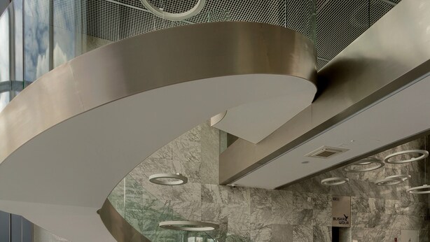 Een moderne lobby met een gebogen trap, marmeren wanden en een receptiebalie.