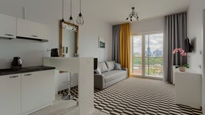 Een modern appartement met keuken, een bank en een groot raam met uitzicht op de stad.