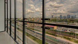 Uitzicht vanaf een hoog gebouw met meerdere verdiepingen, over een stadsbeeld met verschillende gebouwen, wegen en een spoorlijn.