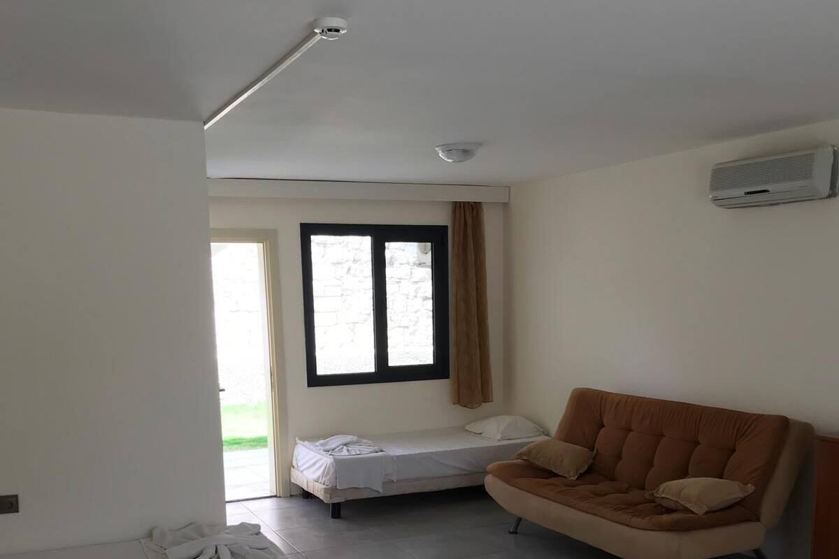 A room with a bed, a sofa, a window with curtains, and a ceiling light.
