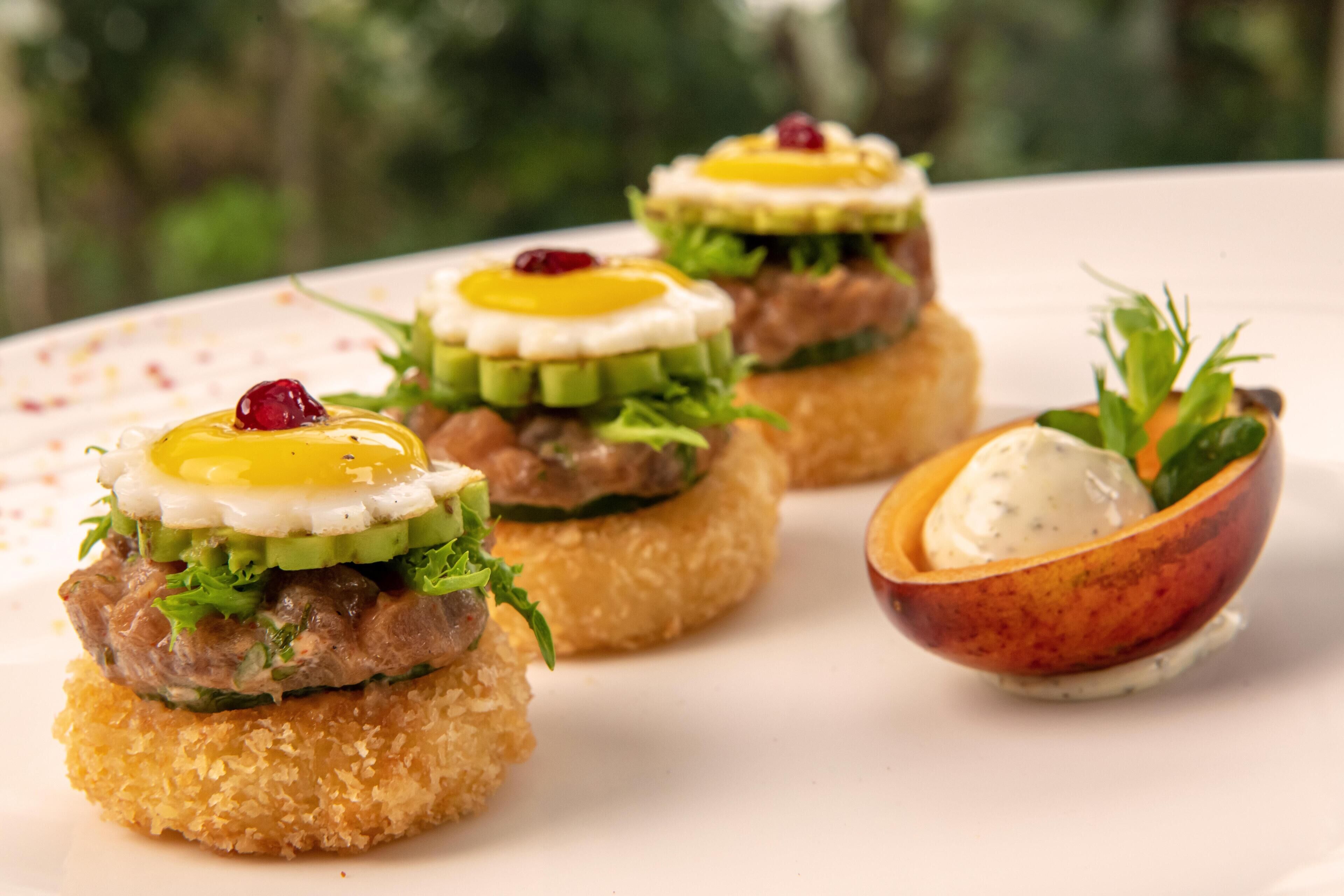 A plate with three food items, each topped with a fried egg and garnished with a berry.
