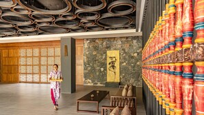 Eine geräumige Lobby mit traditioneller Holzwand, einer Steinwand mit einem gelben Kunstwerk und einer Reihe farbenfroher Säulen.