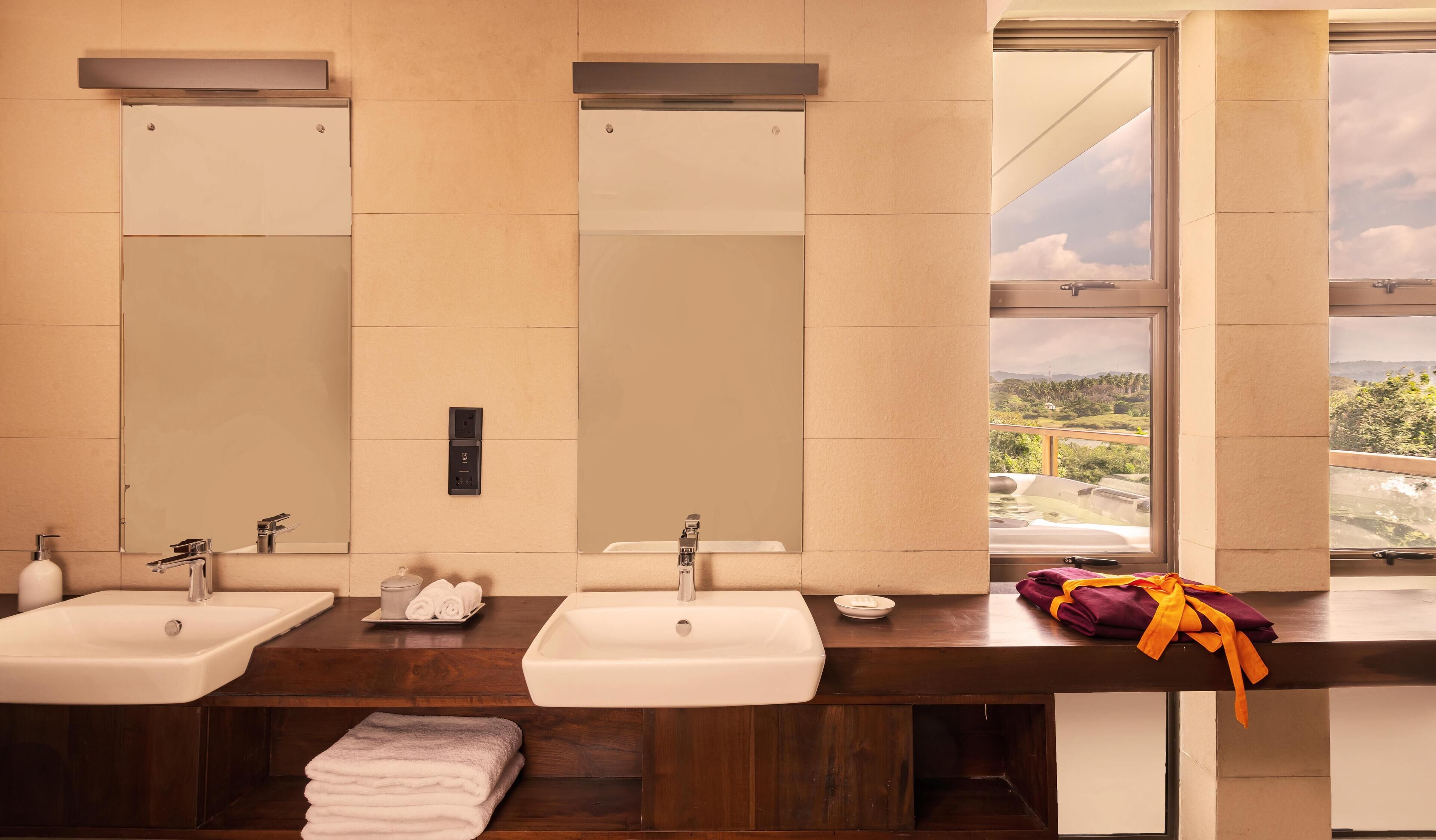 A bathroom with two sinks, a mirror, and a window with a view of a landscape.