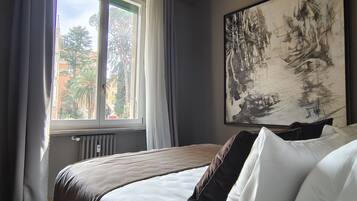Ein Schlafzimmer mit einem Bett, einem Fenster mit Vorhängen, einer Heizung und einem Bild an der Wand.