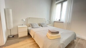 Et pænt opredt soveværelse med seng, sengeborde og et vindue med gardiner.