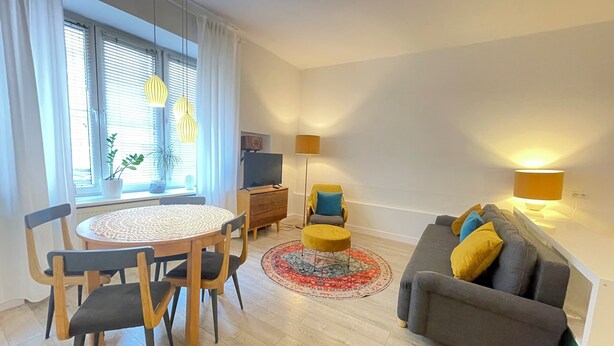En moderne stue med et rundt spisebord, en sofa og et fjernsyn.