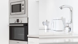 Et køkken med en Bosch ovn, en mikroovn og en moderne vandhane i rustfrit stål.
