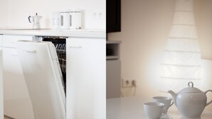 Et moderne køkken med hvide hårde hvidevarer, opvaskemaskine og bord med tekedel og kopper.