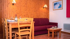 Una habitación con paneles de madera, una mesa de comedor, sillas, un sofá y una pequeña mesa con tazas.