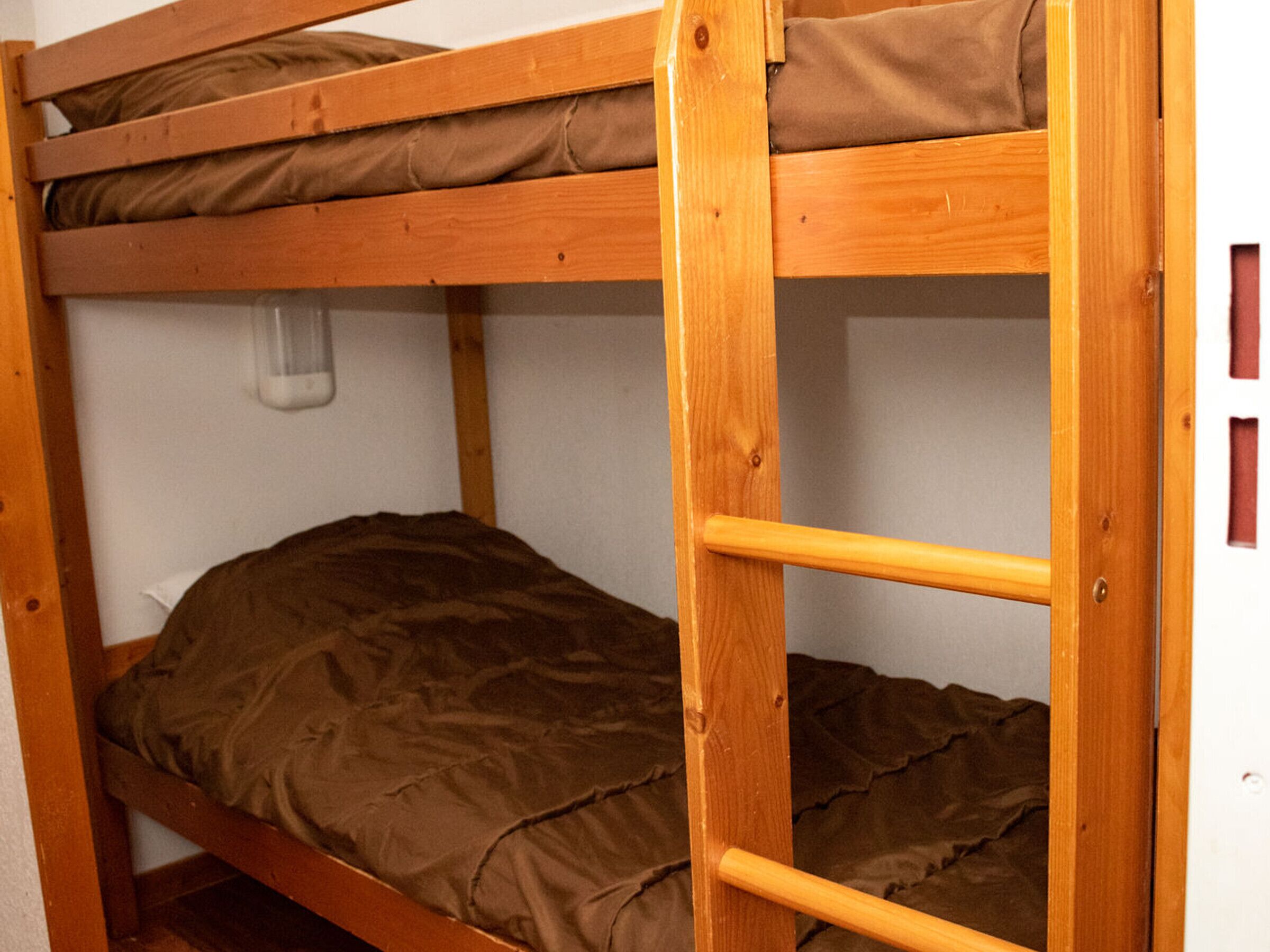 Een stapelbed met houten frame en bruin beddengoed.