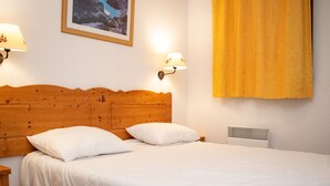 Una cama bien hecha con sábanas blancas, cabecera de madera y dos lámparas de noche.