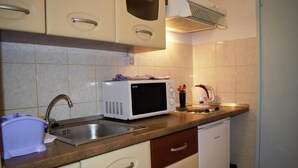 A compact kitchen with a sink, a microwave, a kettle, and a small refrigerator. - Leela Apartment (Dubrovnik)