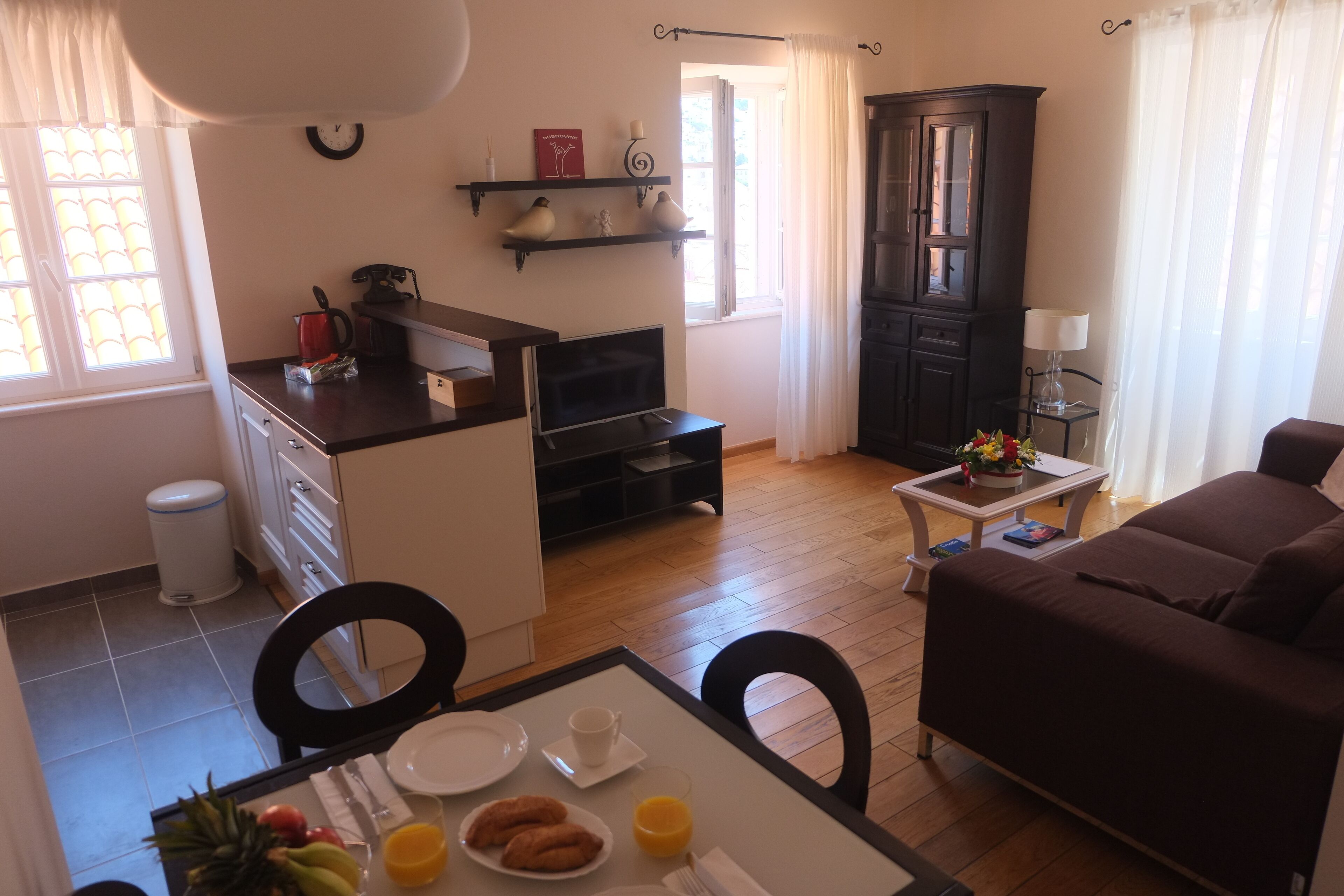 Un espacio habitable compacto con kitchenette, comedor y zona de estar.