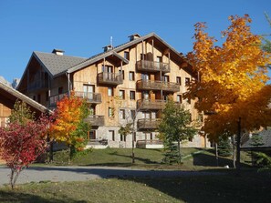 Ein mehrstöckiges Holzgebäude mit Balkonen, umgeben von Herbstlaub.