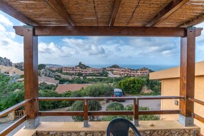 A wooden pergola overlooking a coastal village with traditional buildings and a car parked below. - Bella Vista (Trinità d'Agultu e Vignola)