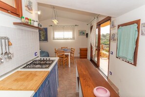 Une cuisine compacte équipée d’une cuisinière à gaz, d’un plan de travail en bois et d’un coin repas avec une table et des chaises.