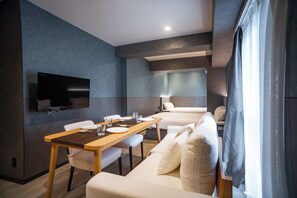 A modern hotel room with a dining area, a sofa, and a TV mounted on the wall. - Kabin Shiro - Regale Collection (Osaka)