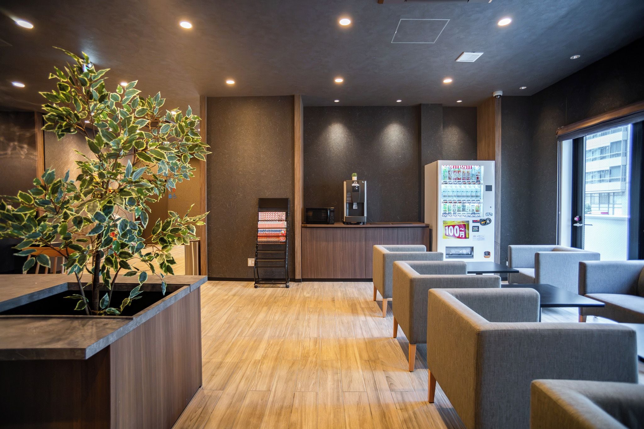 Un espace d’attente moderne comprenant un comptoir d’accueil, des sièges, un distributeur automatique et une plante.