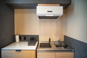 A modern kitchen with a built-in stove, a sink, and a range hood. - Kabin Shiro - Regale Collection (Osaka)