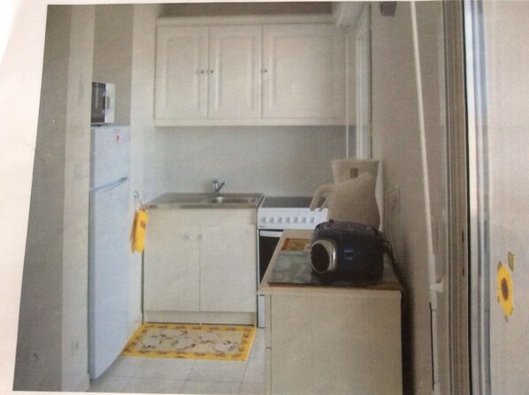 A compact kitchen with white cabinets, a sink, and a stove. - Penthouse apartment in Agde (34) 2 rooms 40 m2, terrace 26 m2 (Agde)