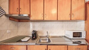 Une cuisine dotée de meubles en bois, d’un évier en acier inoxydable, d’un four à micro-ondes et d’une machine à café.
