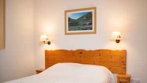 A bedroom with a wooden headboard, a single bed with white bedding, two wall-mounted lamps, and a framed landscape picture on the wall. - Duplex chalet 4 rooms, 8 pers, pets allowed, Superdevoluy (Le Dévoluy)