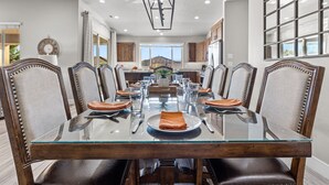 A dining room with a glass-top table, wooden chairs, and a view of the kitchen. - Paradise Village 115, Poolside Heaven, has a Private Hot Tub, and View of Lazy River (Santa Clara)