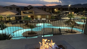 A swimming pool with a fire feature, surrounded by a fence and residential buildings in the background. - Paradise Village 115, Poolside Heaven, has a Private Hot Tub, and View of Lazy River (Santa Clara)