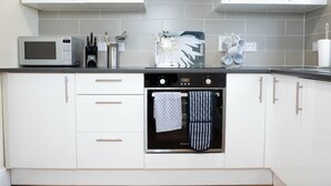 Une cuisine moderne avec des meubles blancs, un four à micro-ondes, un lave-vaisselle et un petit four.
