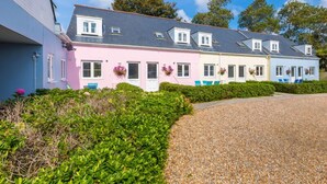 Une rangée de maisons aux couleurs vives, avec une allée en gravier et une végétation luxuriante.