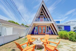 A triangular-shaped building with a balcony, outdoor seating area with chairs, and a small table with a basket. - Iconic A-Frame - Beach Block Dewey! Sleeps up to16! Walk Everywhere! (Dewey Beach)