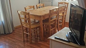 A dining area with a wooden table and chairs, a television on a stand, and a window with curtains. - Duplex Chalet 3 Rooms for 6 People in Superdévoluy (Le Dévoluy)